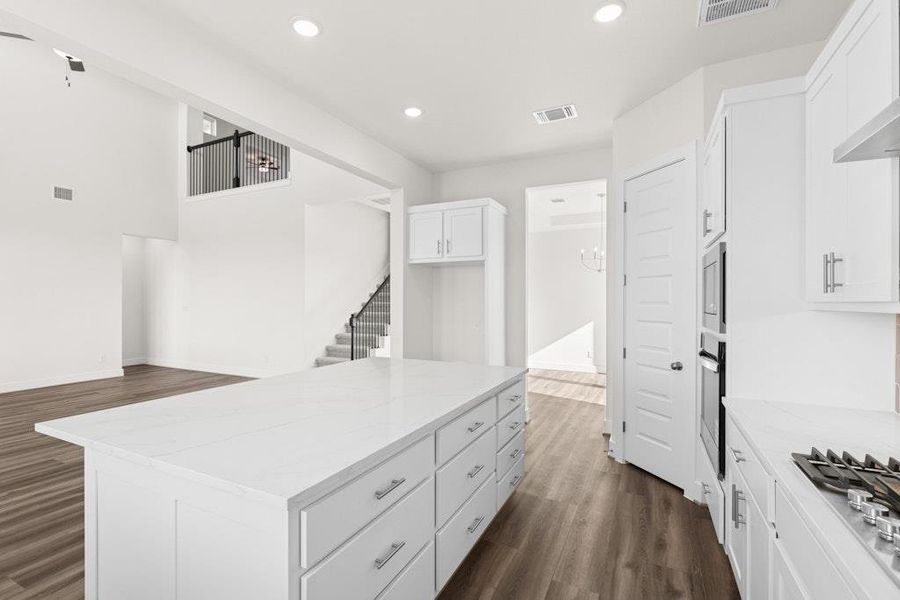 Kitchen featuring white cabinetry, a center island, recessed lighting, dark wood-style floors, and appliances with stainless steel finishes Kitchen featuring white cabinetry, a center island, recessed lighting, dark wood-style floors, and appliances with stainless steel finishes