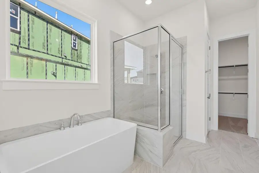 Bathroom with a freestanding bath, a walk in closet, a shower stall, recessed lighting, and marble finish floors Bathroom with a freestanding bath, a walk in closet, a shower stall, recessed lighting, and marble finish floors