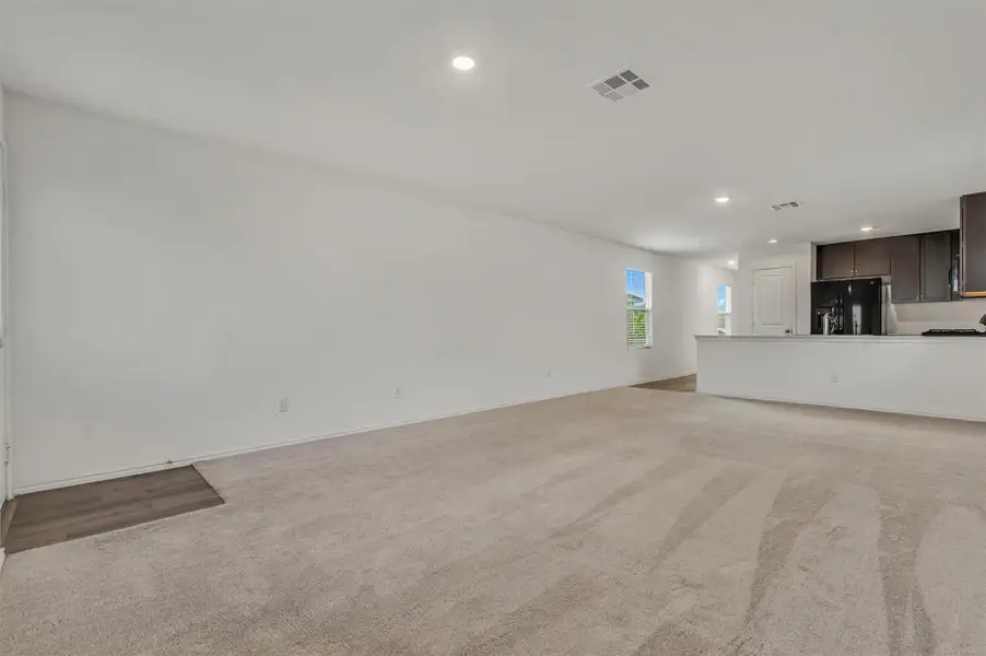 An open living area transitions seamlessly into the kitchen under a smooth, high ceiling. An open living area transitions seamlessly into the kitchen under a smooth, high ceiling.