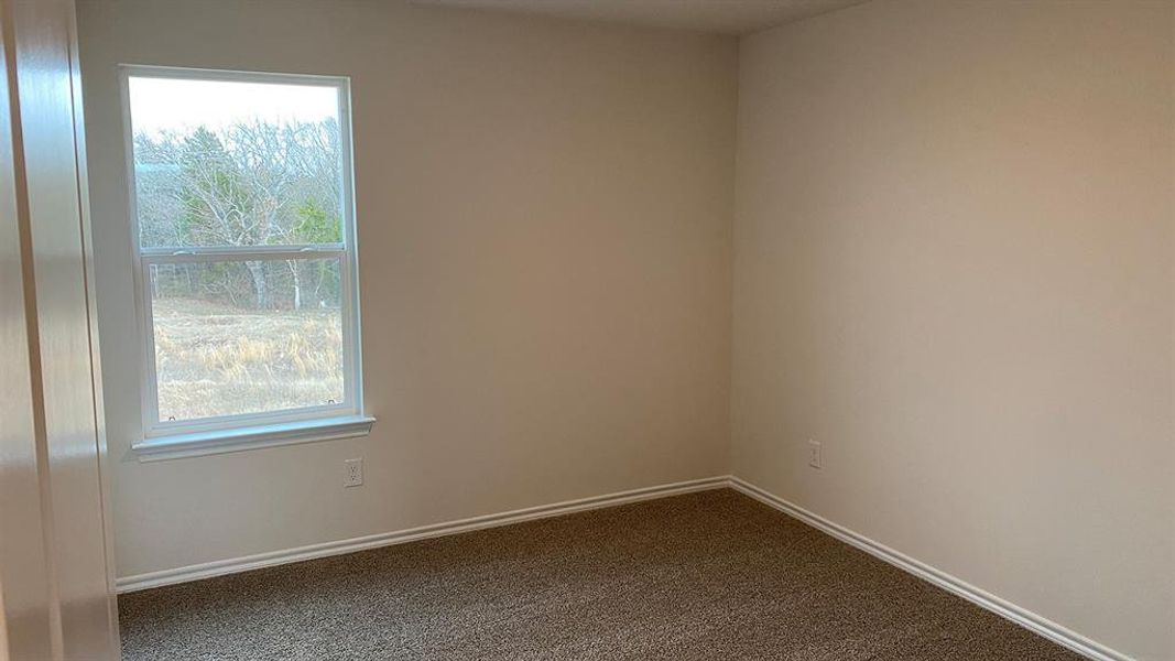 Empty room with dark colored carpet and baseboards