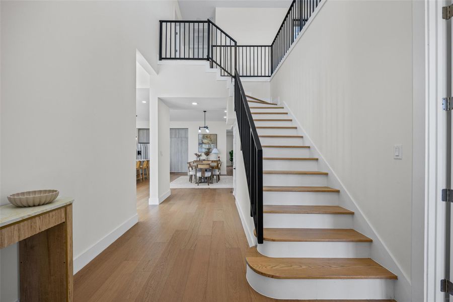 Stairs with wood finished floors, a high ceiling, and recessed lighting
