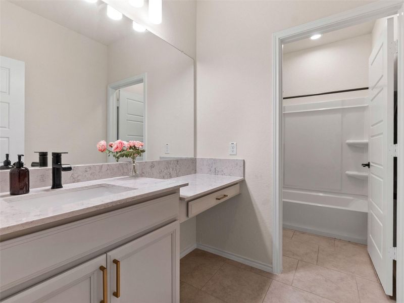 Full bath featuring vanity, light tile patterned floors, and tub / shower combination