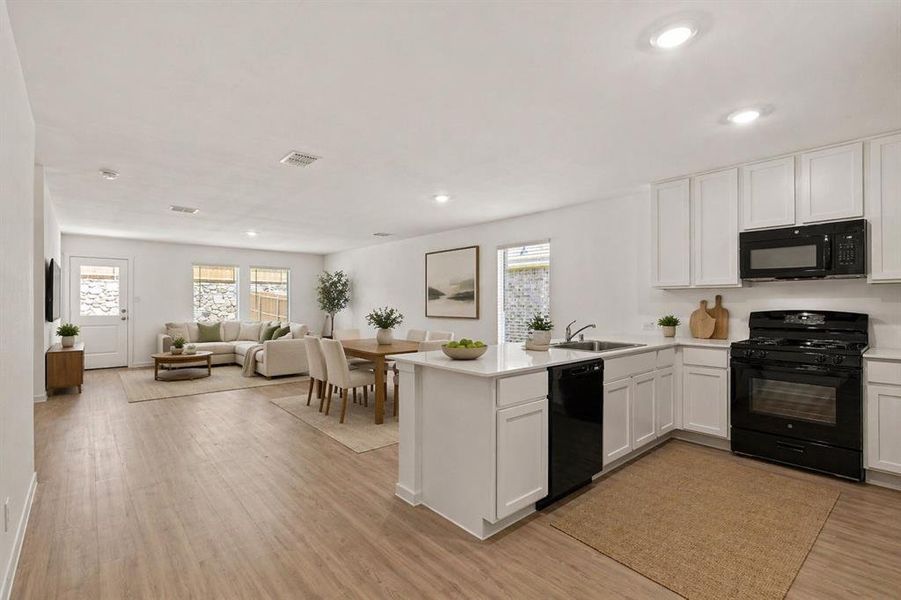 Open-concept living space featuring wood-finish flooring, recessed lighting, and white walls throughout