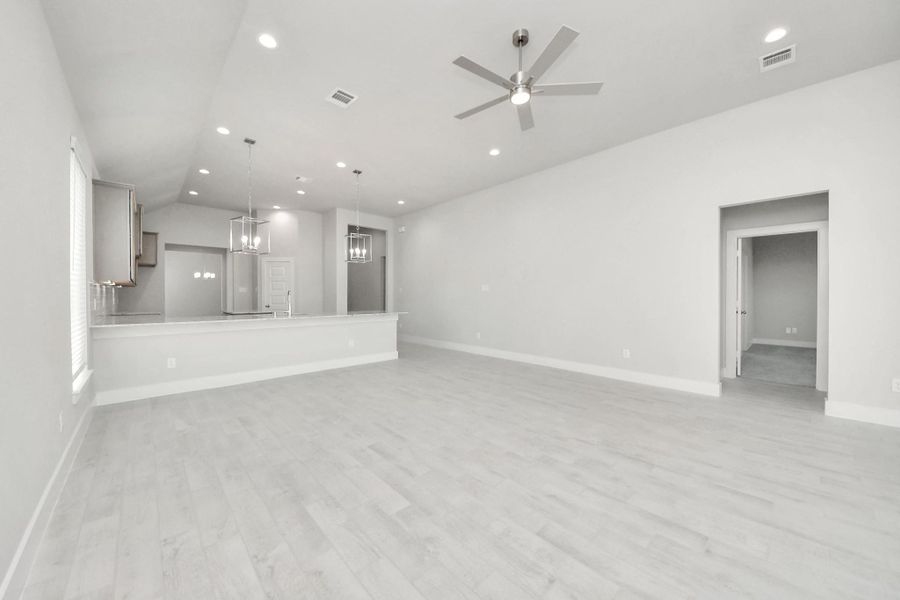 Relax and unwind in this inviting family room, illuminated by abundant natural light streaming in through tall windows, complemented by high ceilings and stunning flooring. Stay comfortable year-round with the gentle breeze from the ceiling fan, creating the perfect atmosphere for family gatherings. Sample photo of completed home with similar floor plan. Actual colors and selections may vary.