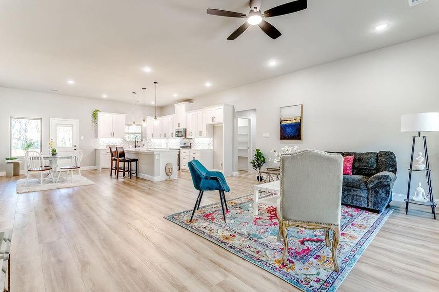 Living room featuring light wood-type flooring, ceiling fan, and sink