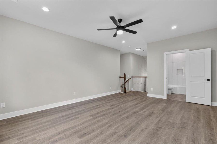 A spacious upper-level area offers versatile living space with light wood flooring, a ceiling fan, and recessed lighting. A spacious upper-level area offers versatile living space with light wood flooring, a ceiling fan, and recessed lighting.
