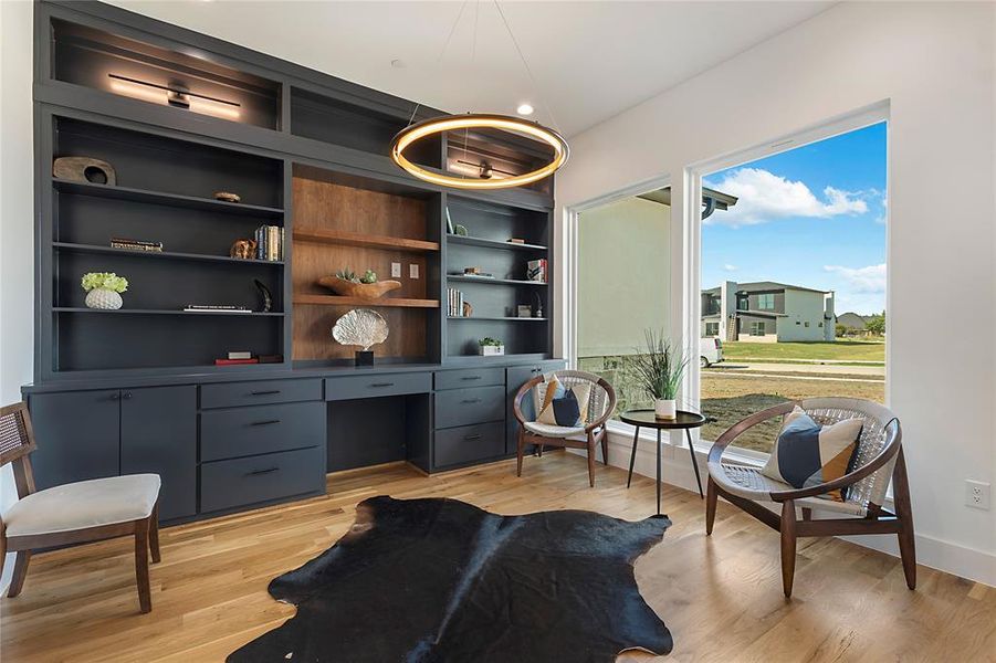 Living area with built in shelves, light wood-type flooring, and built in desk