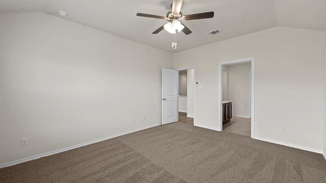 Unfurnished bedroom with dark colored carpet and a ceiling fan