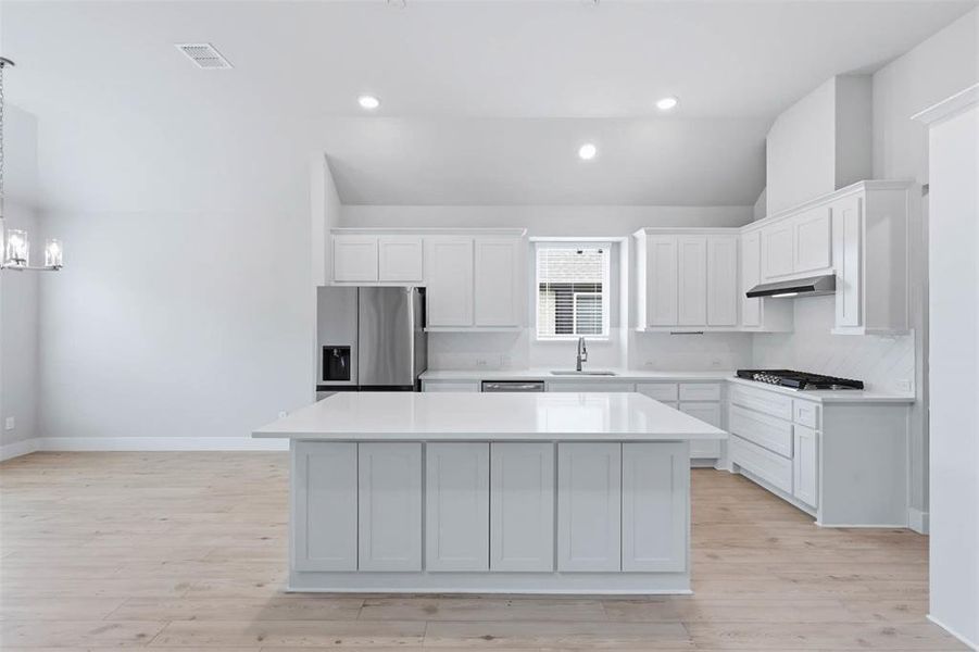 Spacious kitchen with large island, white cabinetry, and open flow to the adjacent living space.