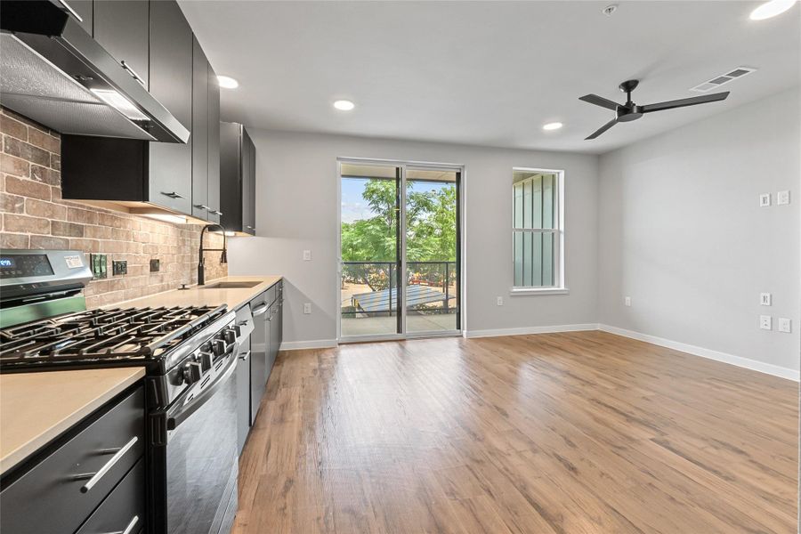 Kitchen with stainless steel appliances, exhaust hood, a ceiling fan, decorative backsplash, and recessed lighting