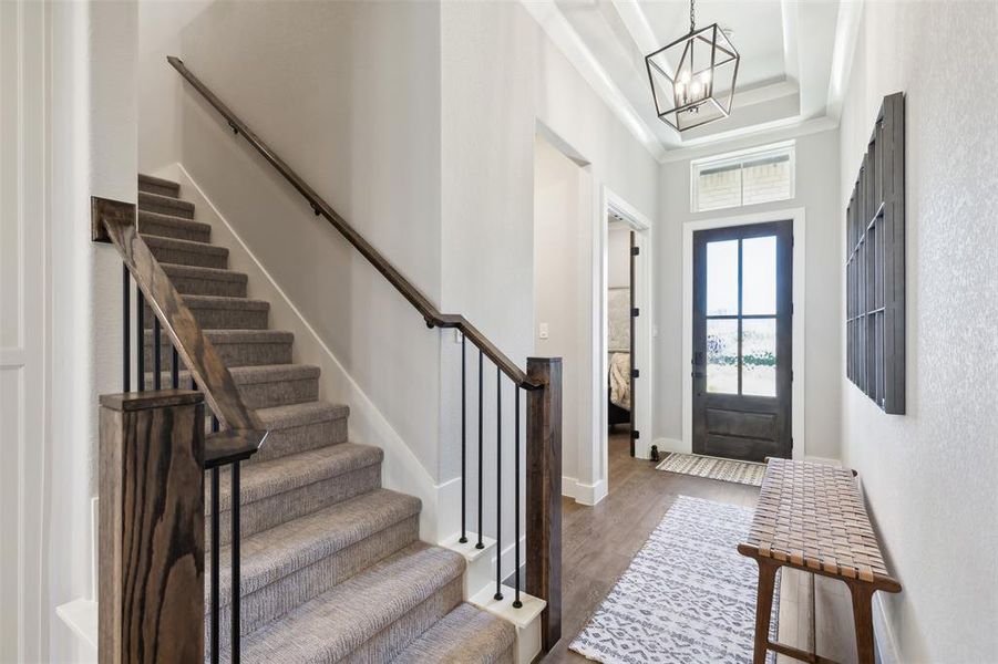 Entrance foyer featuring dark hardwood / wood-style flooring, a high ceiling, and an inviting chandelier