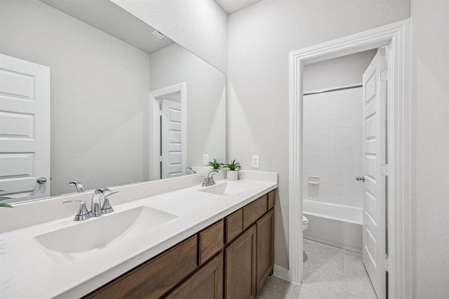 Full bath featuring double vanity, light tile patterned floors, and bathtub / shower combination