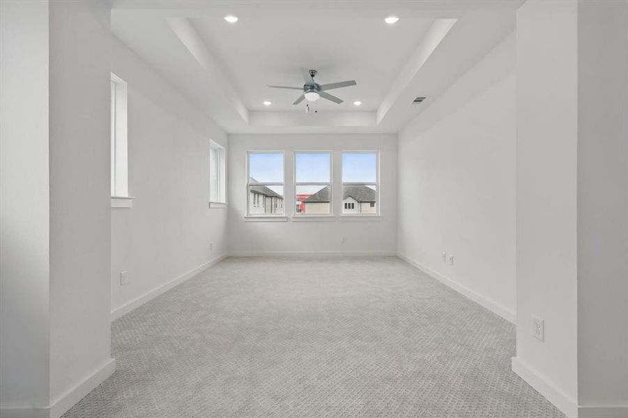 Unfurnished room with a ceiling fan, recessed lighting, light colored carpet, baseboards, and a raised ceiling