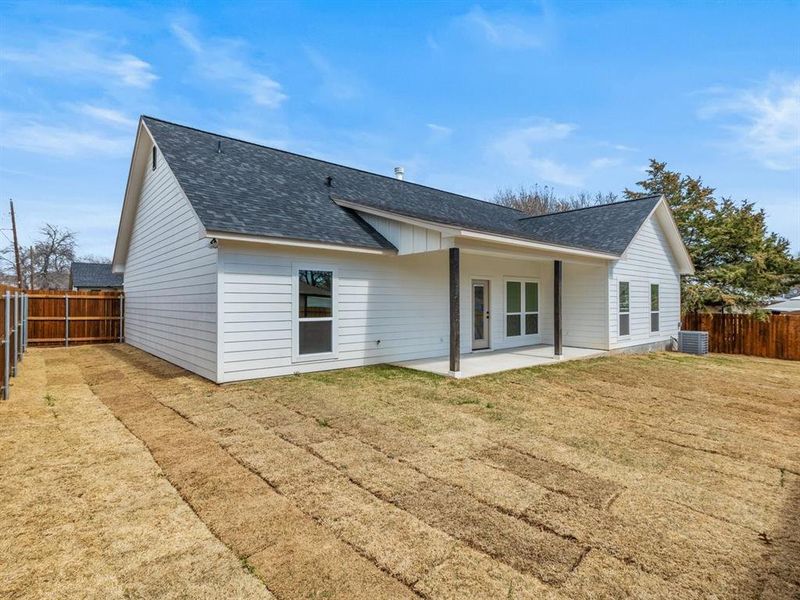 Back of house with roof with shingles, a fenced backyard, and a patio area