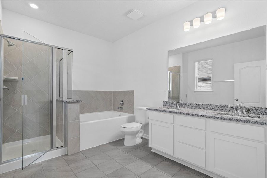 Luxurious primary suite bath boasts a large double vanity topped with elegant granite countertops, a deep soaking tub, and a generously sized standalone glass shower.