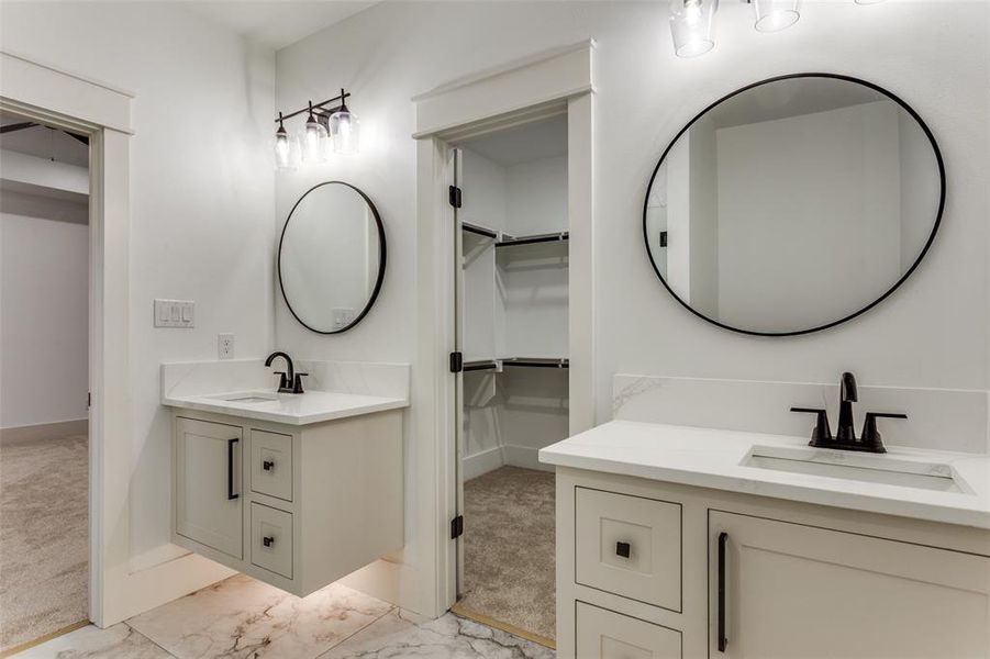 Full bathroom with two vanities, a walk in closet, and light marble finish flooring Full bathroom with two vanities, a walk in closet, and light marble finish flooring