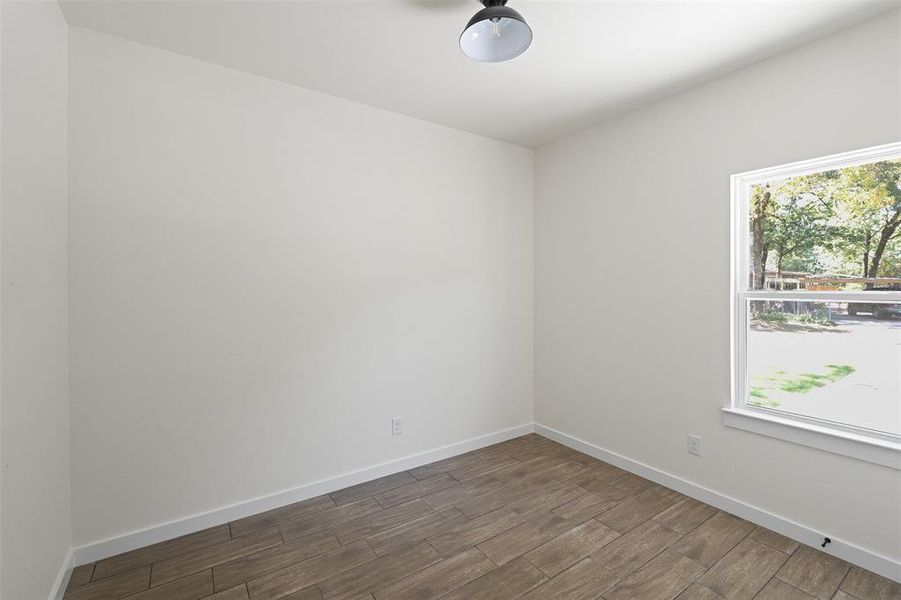 Light-filled room featuring wood-finish flooring, white walls, and a window with outdoor scenery