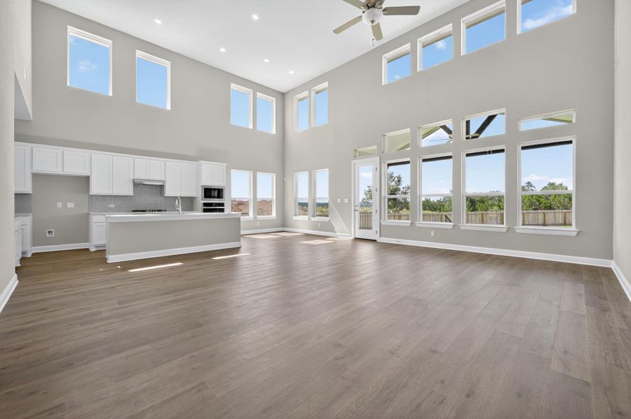 Unfurnished living room with dark wood finished floors, recessed lighting, a towering ceiling, and ceiling fan