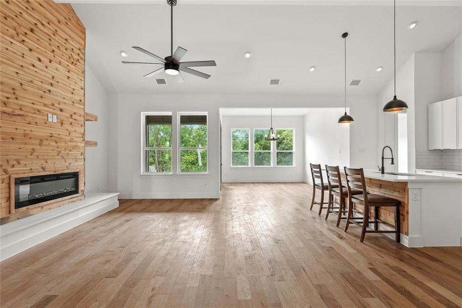Living room featuring a ceiling fan, a fireplace, light wood finished floors, high vaulted ceiling, and recessed lighting