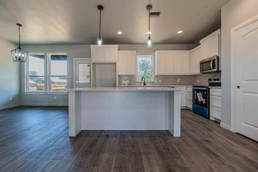 Kitchen featuring electric range oven, tasteful backsplash, stainless steel microwave, white cabinetry, and light countertops Kitchen featuring electric range oven, tasteful backsplash, stainless steel microwave, white cabinetry, and light countertops