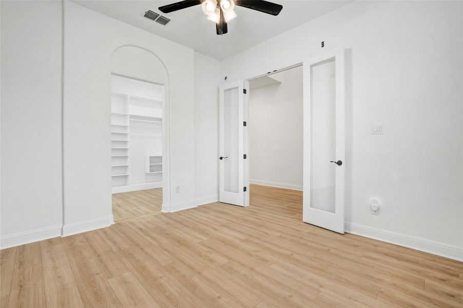 Unfurnished bedroom featuring a walk in closet, light wood-style flooring, and a ceiling fan