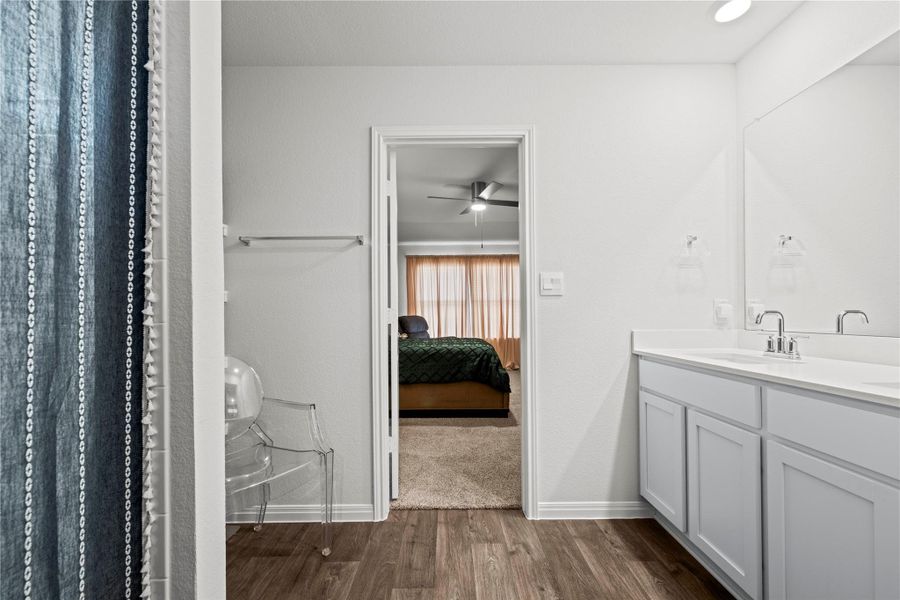 Refined bathroom with a dual vanity, pristine white countertops, and warm wood flooring.