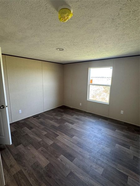 Dark wood-look flooring contrasts beautifully with neutral walls in this versatile bedroom.