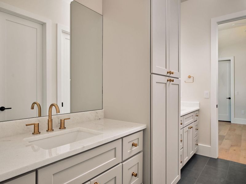 Golden-hued fixtures elevate the luxurious vanity space within this well-appointed bathroom. Golden-hued fixtures elevate the luxurious vanity space within this well-appointed bathroom.