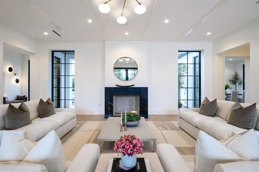 Living area featuring recessed lighting, wood finished floors, a fireplace with flush hearth, and beam ceiling Living area featuring recessed lighting, wood finished floors, a fireplace with flush hearth, and beam ceiling