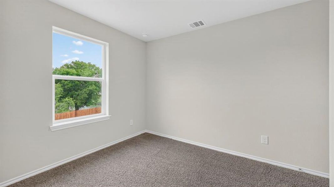 Bright room featuring a single window with white trim, light gray walls, dark gray carpet, and white baseboards