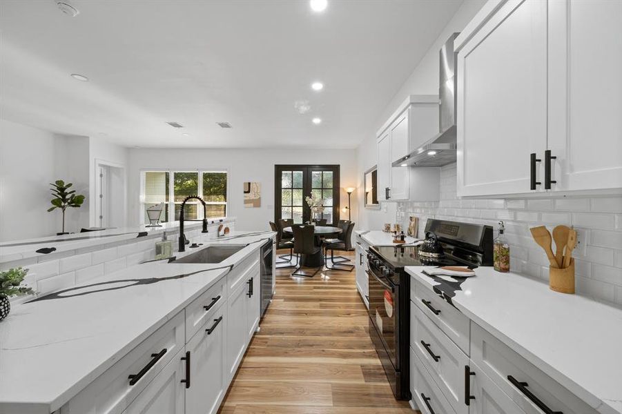 Kitchen featuring white cabinets, sink, light hardwood / wood-style flooring, and light stone countertops