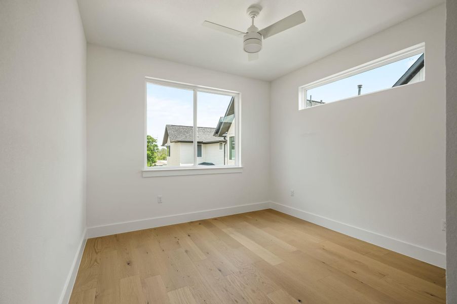 A well-lit bedroom features durable hardwood flooring and a sleek ceiling fan. A well-lit bedroom features durable hardwood flooring and a sleek ceiling fan.