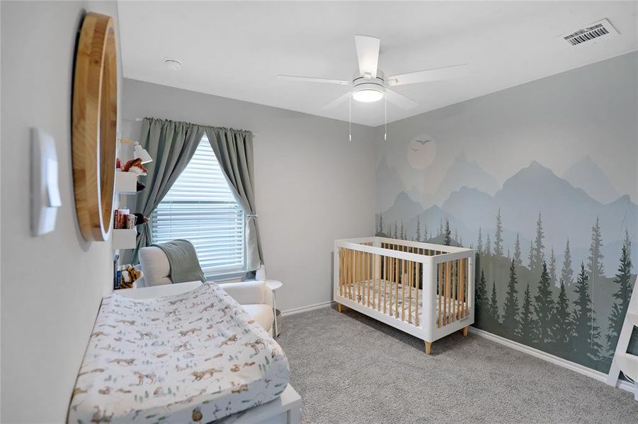 Bedroom with light carpet, a nursery area, and ceiling fan