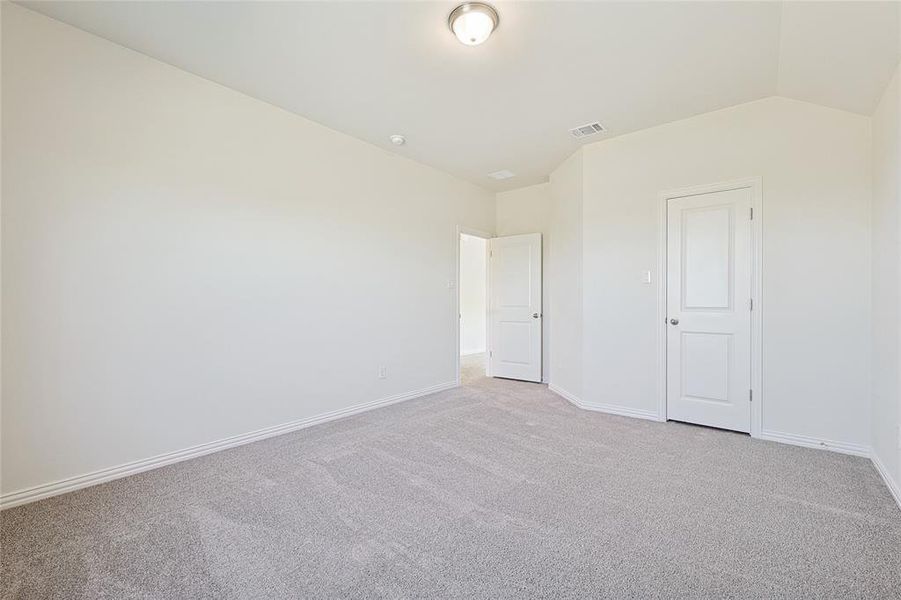 Unfurnished bedroom featuring carpet floors and lofted ceiling