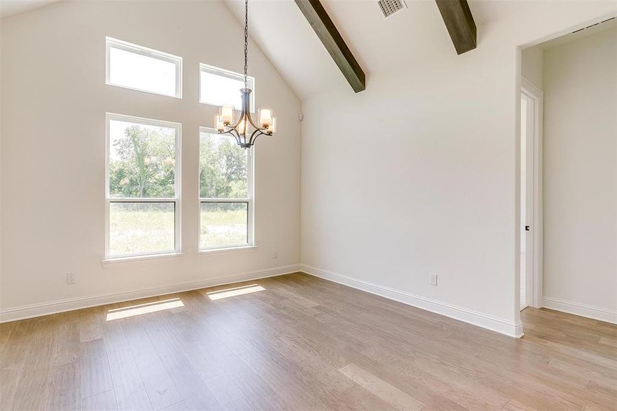 Unfurnished room featuring beamed ceiling, high vaulted ceiling, light wood-type flooring, and a chandelier