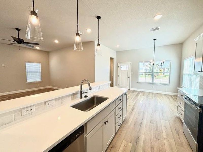 Kitchen with white cabinets, stainless steel appliances, hanging light fixtures, and sink