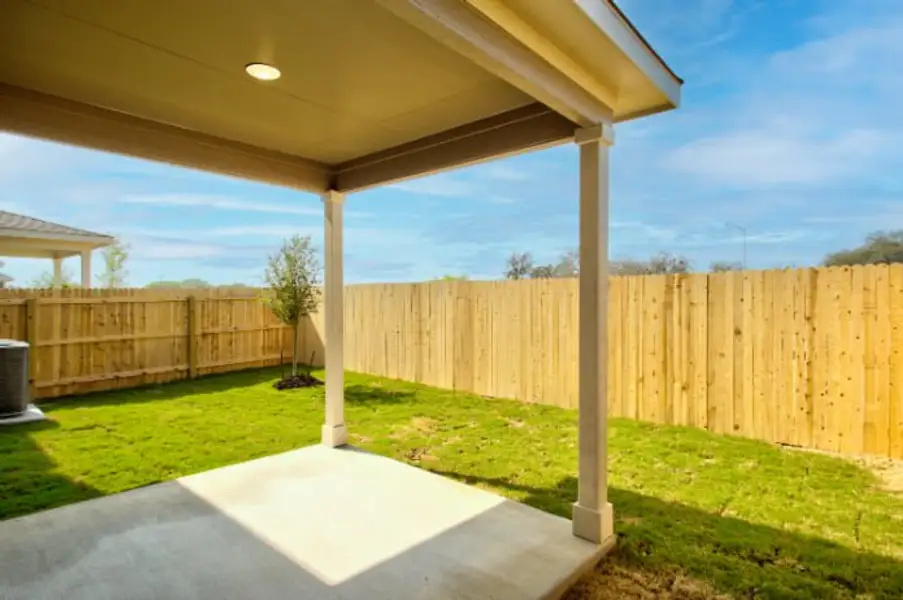 A backyard with a fence and a trampoline.