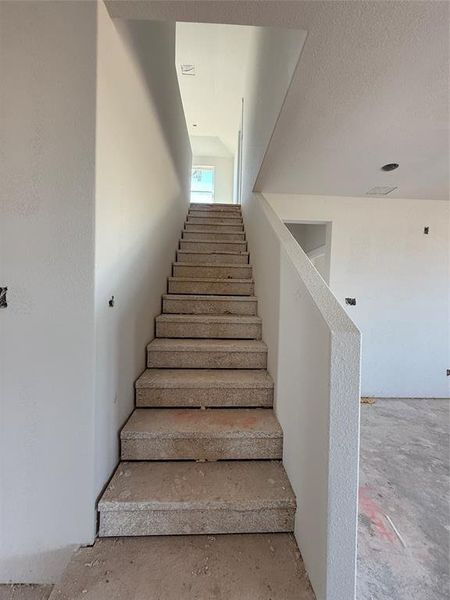 Stairway with a textured ceiling and concrete floors