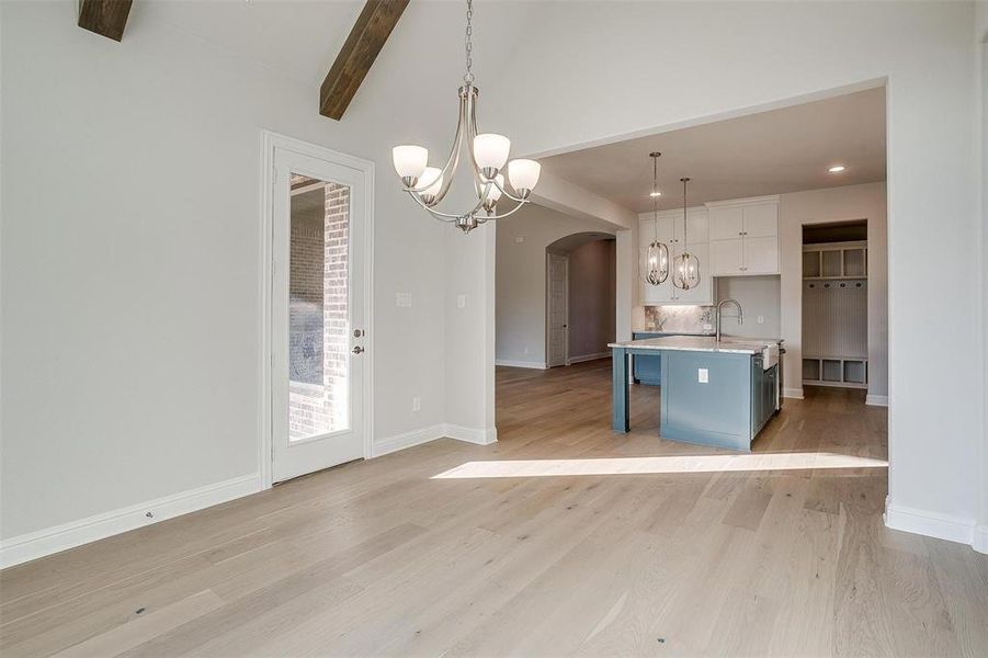 Kitchen with pendant lighting, light hardwood / wood-style floors, a kitchen breakfast bar, and an island with sink