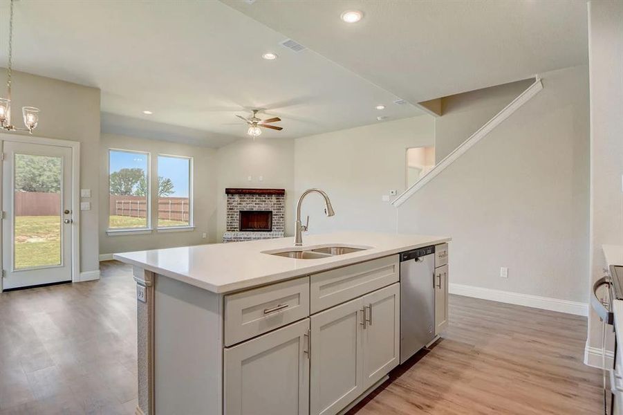 Kitchen with a sink, dishwasher, a ceiling fan, baseboards, and light countertops