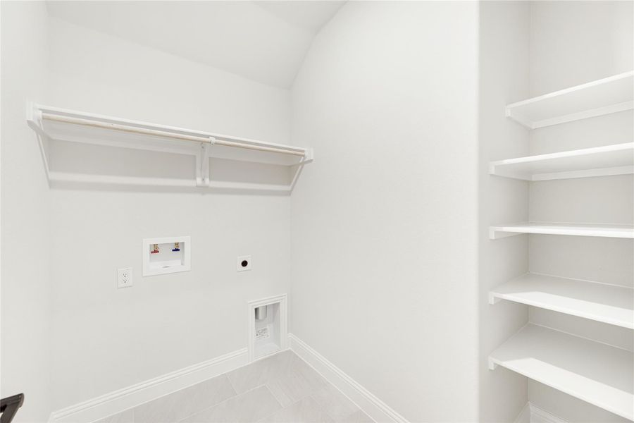 Laundry room with white built-in shelves, hanging rod, washer hookups, and tile floor