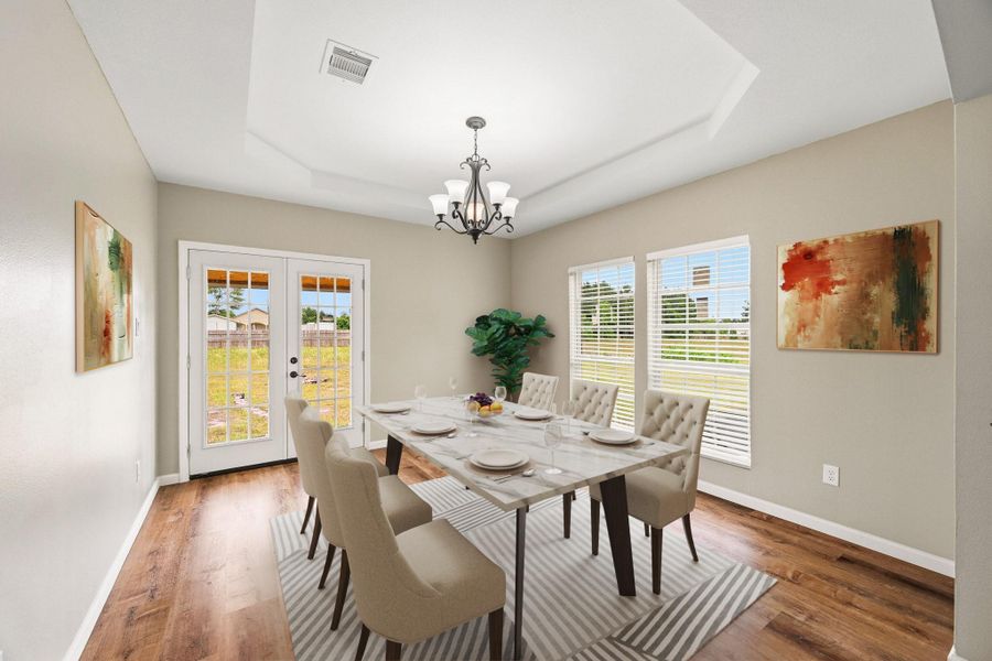 Virtually Staged: The dining area is filled with natural light from surrounding windows and French doors that provide direct access to the backyard, creating an inviting atmosphere for gatherings and indoor-outdoor living.