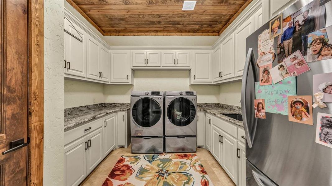 Well-appointed utility space with granite counters, abundant cabinetry, and front-load washer and dryer.
