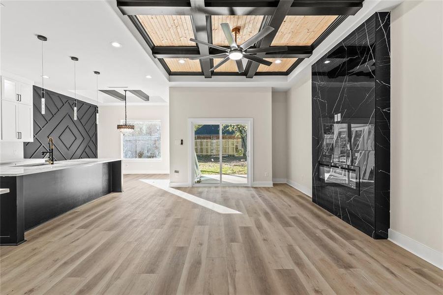 Unfurnished living room with light hardwood / wood-style floors, beam ceiling, and coffered ceiling