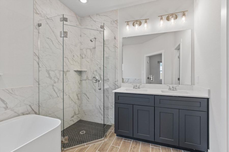 A well-lit bathroom featuring a spacious shower with sleek glass doors and a dual-sink vanity. A well-lit bathroom featuring a spacious shower with sleek glass doors and a dual-sink vanity.