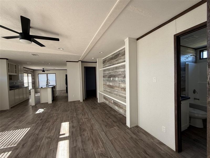 Unfurnished living room with a textured ceiling, dark wood-style floors, and ceiling fan