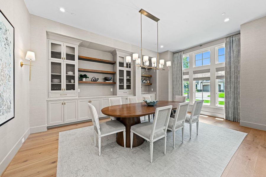Located just off the entry, this stunning formal dining room offers a refined setting for both intimate dinners & larger gatherings. Philip Jeffries grass cloth wallpaper adds warmth & texture, while a Visual Comfort chandelier anchors the space. Thoughtfully designed w/ a built-in wet bar, creating a seamless balance of function & elevated style. Layered shelving, cabinetry w/ metal mesh inserts & additional storage create both visual interest & everyday functionality. Located just off the entry, this stunning formal dining room offers a refined setting for both intimate dinners & larger gatherings. Philip Jeffries grass cloth wallpaper adds warmth & texture, while a Visual Comfort chandelier anchors the space. Thoughtfully designed w/ a built-in wet bar, creating a seamless balance of function & elevated style. Layered shelving, cabinetry w/ metal mesh inserts & additional storage create both visual interest & everyday functionality.