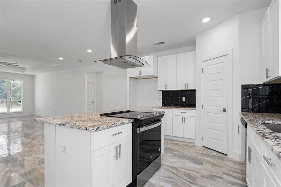 Kitchen featuring light stone countertops, a kitchen island, white cabinetry, island exhaust hood, and stainless steel appliances