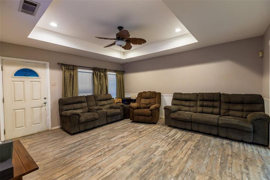 Living area with wood finished floors, a tray ceiling, a ceiling fan, and recessed lighting Living area with wood finished floors, a tray ceiling, a ceiling fan, and recessed lighting