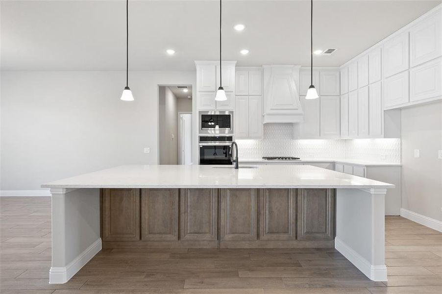 Kitchen with pendant lighting, white cabinetry, a spacious island, light stone counters, and recessed lighting
